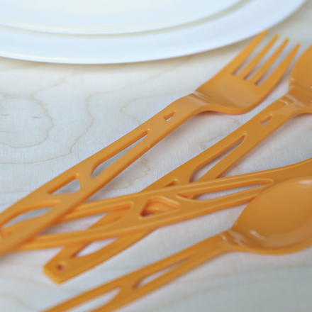 Turvallisuusruokailuvälineet - Oranssit itsemurhaa ehkäisevät ruokailuvälineet pöydälle levitettyinä.