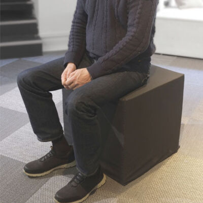 Man sitting on foam cube, seen from sholder down.