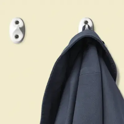 Two suicide resitant hooks on a wall with a hanging jacket
